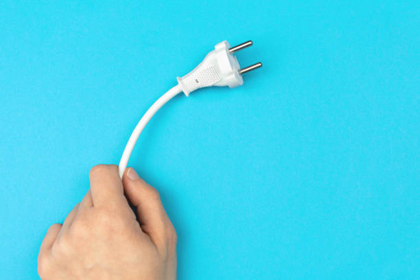 istock Hand holding power cable with EU plug on a bright blue background, flat lay, top view and copy space photo 1351344716