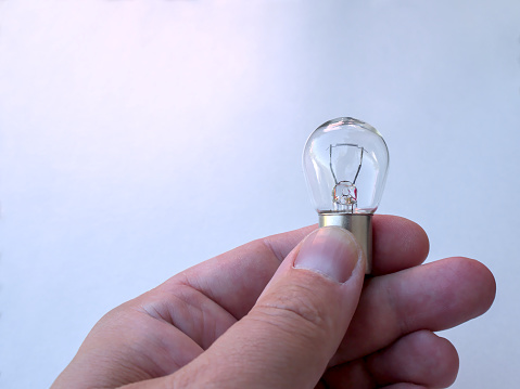 A man holding a small light bulb for a car