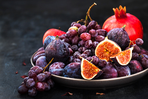 Fresh autumn fruits -  figs, plums, grapes and pomegranate on dark background