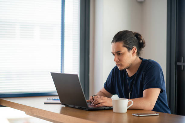istock Happy young man using his laptop while sitting in the office 1351347223
