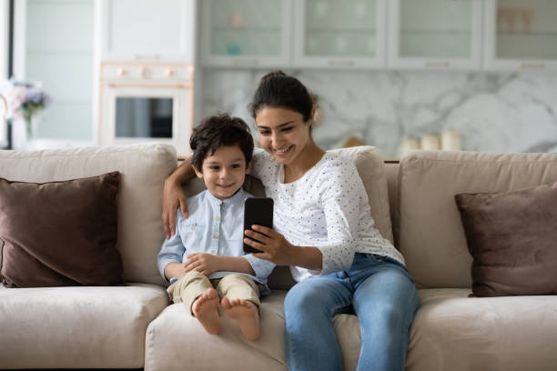 istock Smiling bonding young indian woman using cellphone with small kid. 1351347317