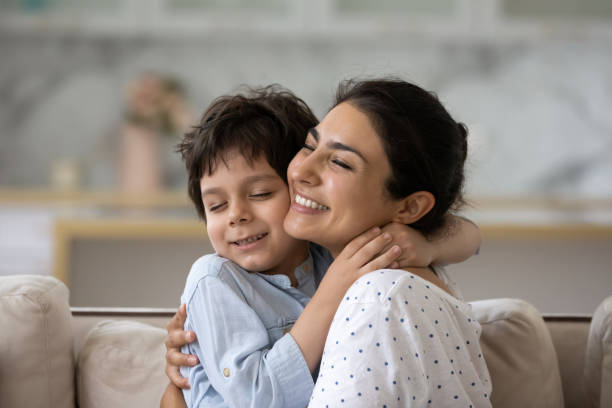 Loving indian ethnicity family showing tender relations. Sincere loving young asian indian woman cuddling cute little kid son, showing tender feelings. Happy two generations mixed race family enjoying sweet weekend moment together, relaxing at home. foster care stock pictures, royalty-free photos & images