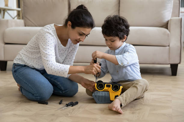 Happy young indian mother fixing toy car with little son. Happy young indian ethnic mother helping adorable small kid son fixing toy car with screwdriver, playing together at home. Smiling asian mum teaching little child repairing, developing motility skills screwdriver photos stock pictures, royalty-free photos & images