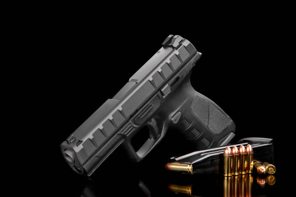 istock Black modern gun and ammunition for it on a dark reflective surface. Short-barreled weapons for sports and self-defense. Armament for police units, special forces and the army. Black background 1351349977