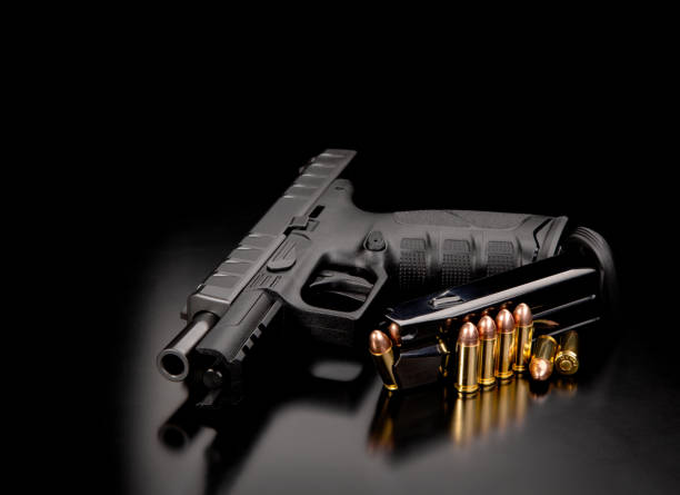 istock Discharged weapon. Black modern gun and ammunition for it on a dark reflective surface. Short-barreled weapons for sports and self-defense. Armament for police units, special forces and the army. 1351349980