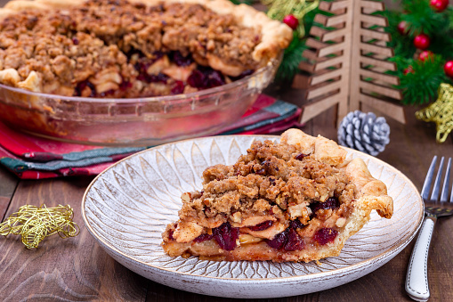Freshly baked American apple cranberry pie, topped with crumbled dough and pecan, closeup