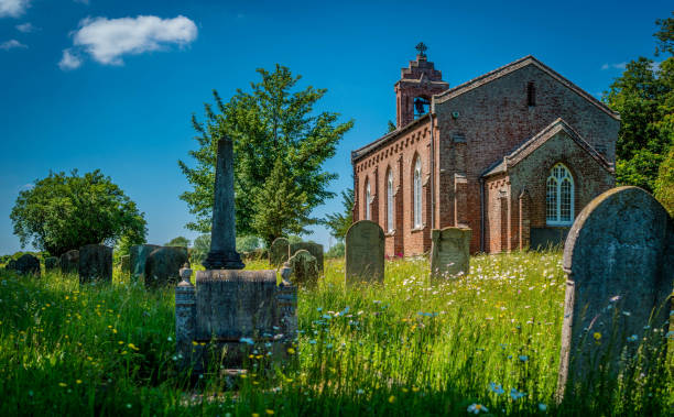 St Margaret of Scotland Church external and graveyard with long grass on a bright summer's day