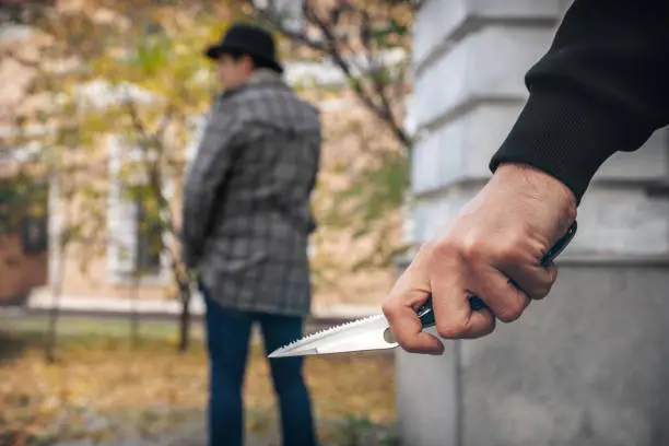 A man holding a knife in his hand ready to attack a man. Crime is on the rise.