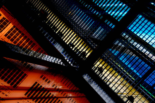 istock Colorful industrial architecture in bright orange, yellow and blue backlight. DIgitally rendered abstract architectural composition featuring shiny metal girders, grid structures and louvered walls. 1351358484