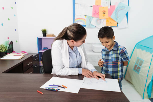 istock Female psychologist looking at boy's drawing and pointing 1351358558