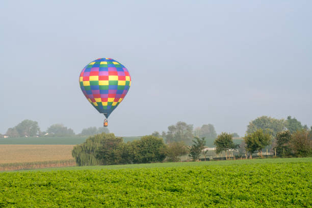 istock Hot air balloon flying over farmland 1351358567