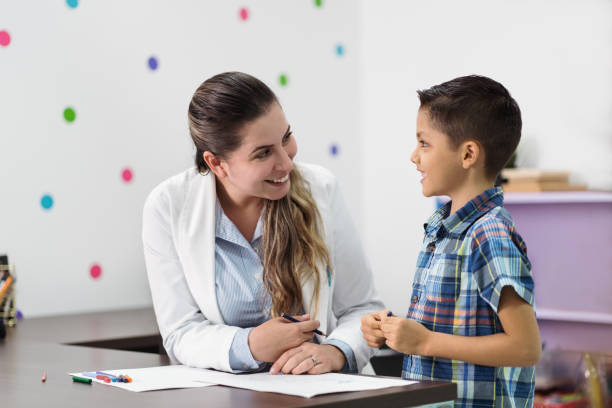 feliz psicólogo y niño sonriendo el uno al otro - profesional de salud mental fotografías e imágenes de stock