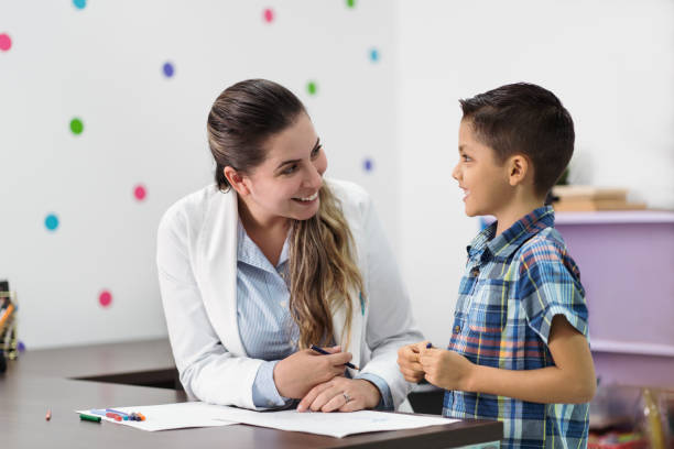 Happy psychologist and little boy smiling at each other stock photo