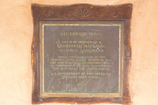 Taos, NM: A bronze historic plaque on the Kit Carson house and museum in downtown Taos, NM.