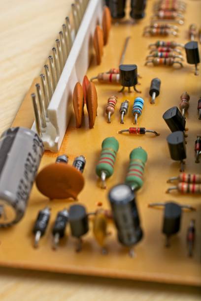 istock Close-up printed circuit board with discrete diodes resistors integrated circuit chip on wooden workbench 1351360533