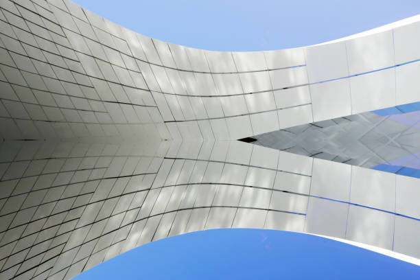 istock Computer graphic image of matte walls against blue sky background. Curvilinear architectural surfaces. Abstract glass background on the subject of modern architecture, construction industry or technology. 1351361735