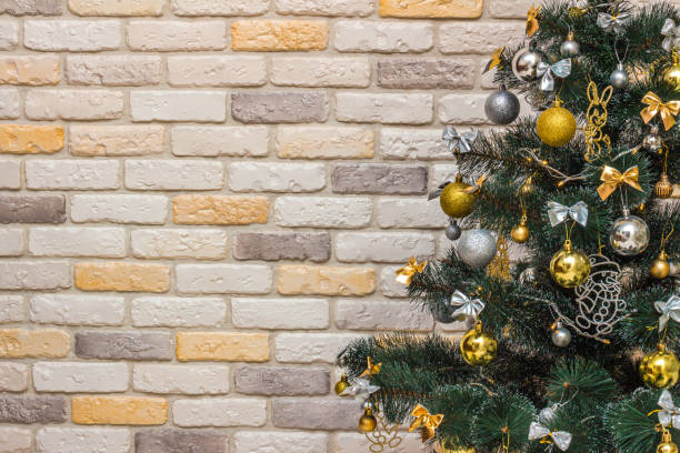istock Mockup with decorated Christmas tree. Composition with gold and silver baubles, bows, animals, bells, lit garlands. Copy-space on the decorative brick wall background. Close-up, selective focus 1351371950