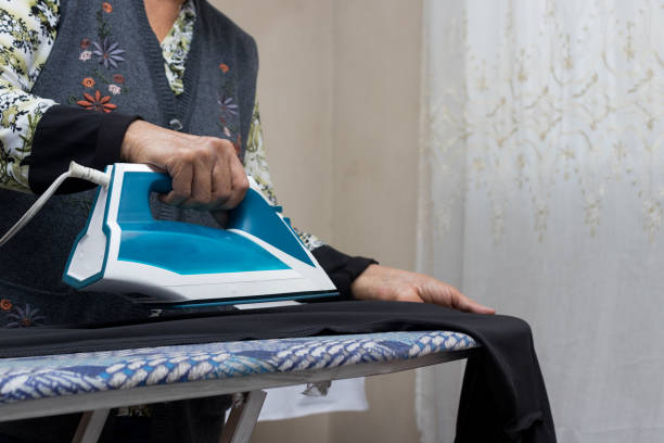 женщина гладит одежду - iron women ironing board stereotypical housewife стоковые фото и изображения
