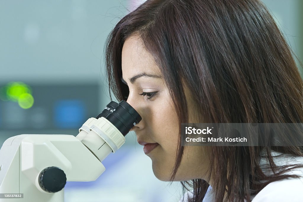 Donna facendo ricerca guardando attraverso un microscopio - Foto stock royalty-free di Adulto
