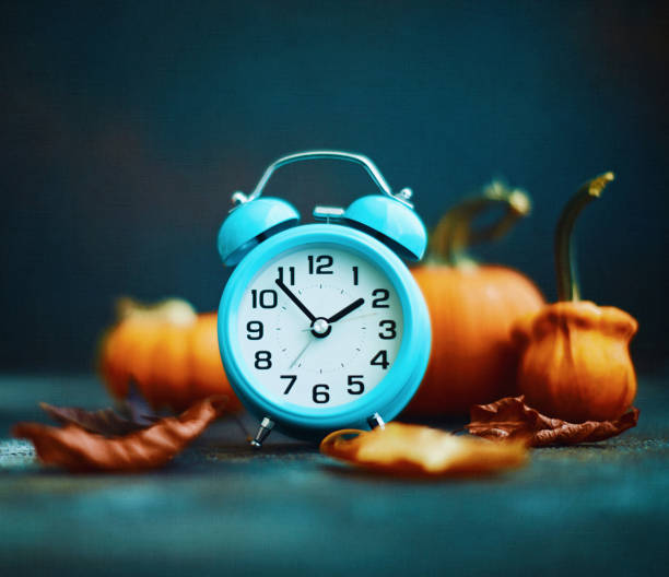 istock Teal Alarm Clock with Fall Decorations for Daylight Savings Time 1351381059