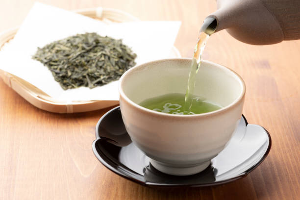 warmer grüner tee auf einem holztisch. - teepflanze stock-fotos und bilder