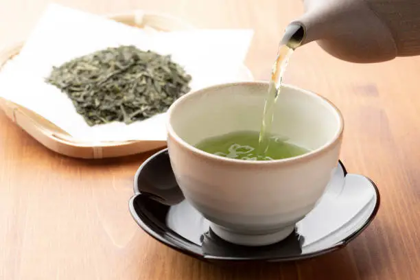 Photo of Warm green tea on a wooden table.