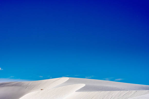 istock Blue Sky Over Winding Crest Of White Sand Dunes 1351384969