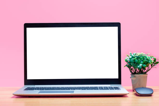 istock Laptop with white blank screen on wooden table on a pink background. 1351388755