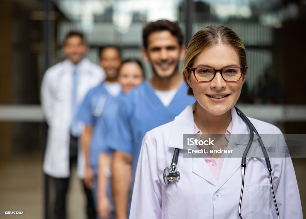 Doctor leading a group of healthcare providers at the hospital Female Latin American doctor leading a group of healthcare providers at the hospital standing in a row and looking at the camera smiling - healthcare and medicine concepts Civilian Stock Photo