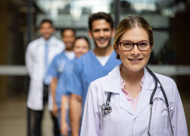 Doctor leading a group of healthcare providers at the hospital Female Latin American doctor leading a group of healthcare providers at the hospital standing in a row and looking at the camera smiling - healthcare and medicine concepts civilian stock pictures, royalty-free photos & images
