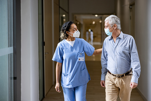 Doctor talking to a patient in the corridor of a hospital while wearing face masks