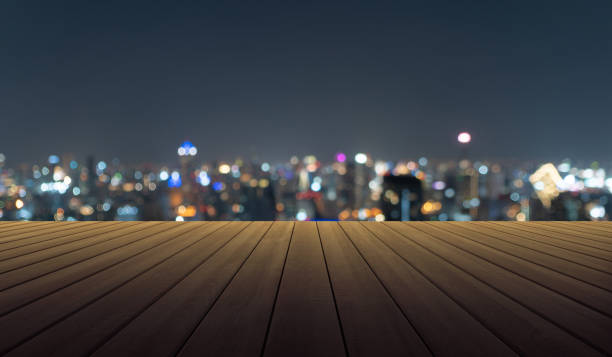 empty table board with bokeh abstract background of skyscraper buildings in urban city with lights, blurry photo at night time. cityscape. - street furniture traffic lighting equipment urban scene imagens e fotografias de stock