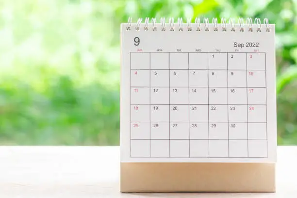September month, Calendar desk 2022 for organizer to planning and reminder on wooden table with green nature background.
