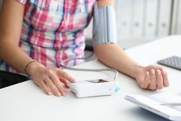 istock Woman sitting at table measures blood pressure with automatic tonometer 1351405773