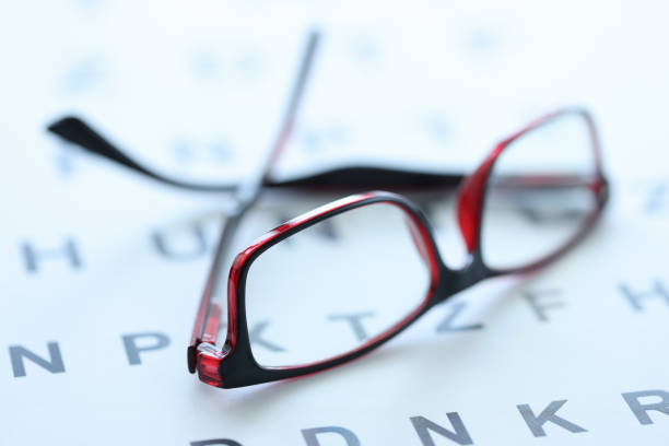 Stylish glasses in black and red frames lie on ophthalmic table closeup
