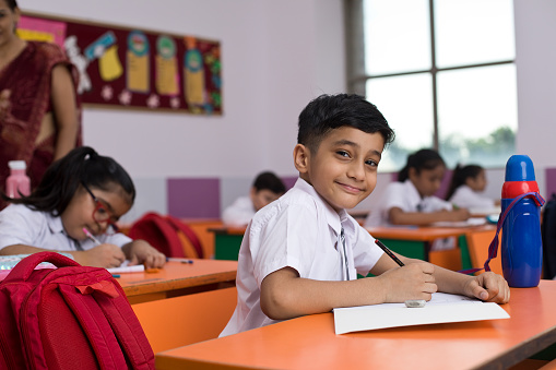 Learning, question and hands raised with girl in classroom for education, discussion and knowledge. Help, studying and teacher with children and woman at school for why, scholarship and answer