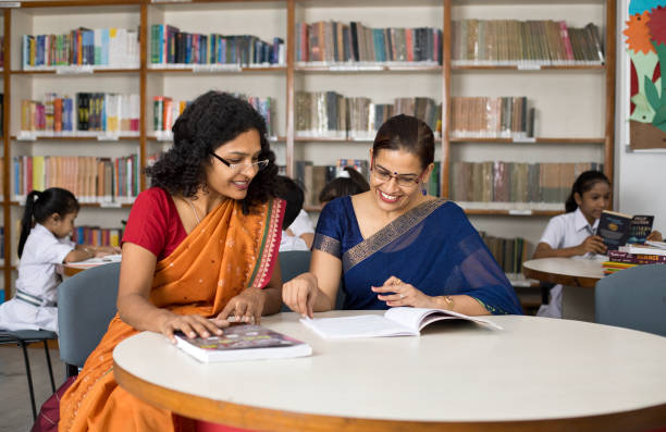 istock Two teachers discussing over books in library 1351410782