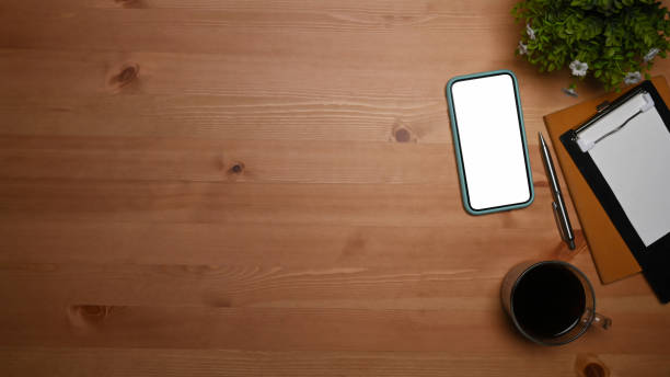 istock Mock up mobile phone, coffee cup and notebook on wooden table. 1351410791