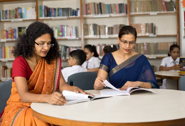 istock Two female teachers checking books in library 1351410807