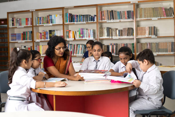 istock Female teachers teaching students in library at school 1351416129