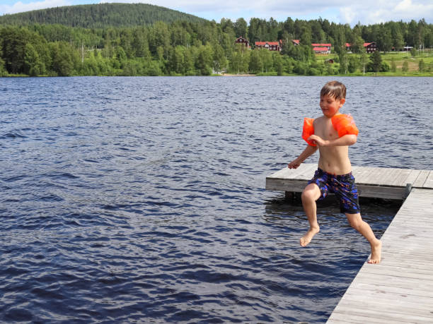 istock Boy jumping Into the water from jetty 1351416186