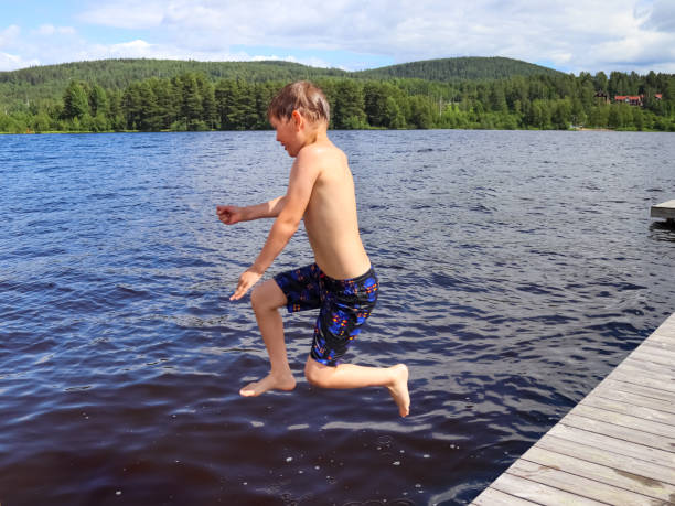 istock Boy jumping Into the water from jetty 1351416187