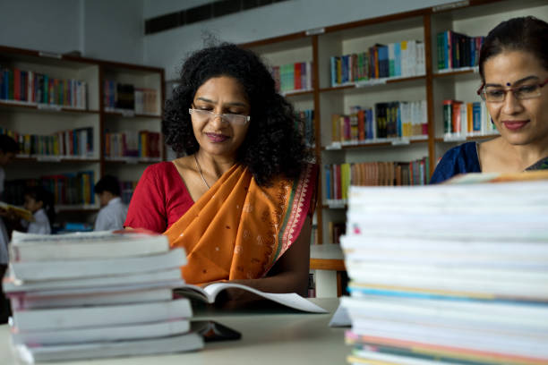 istock Two teachers writing and reading books in library 1351416247