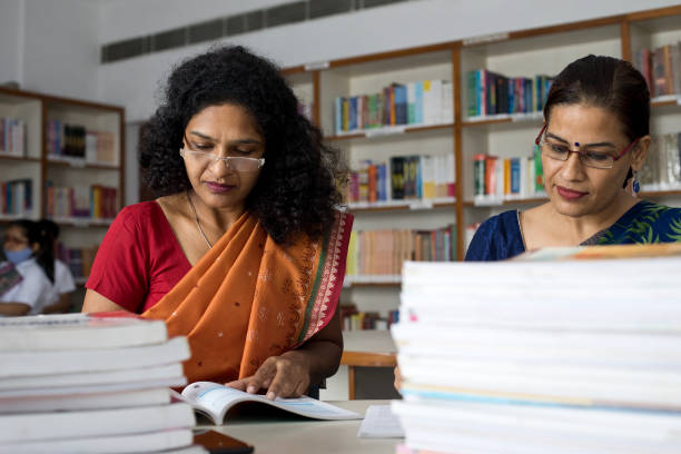 istock Two teachers writing and reading books in library 1351416328