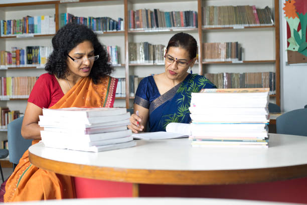 istock Two teachers writing and reading books in library 1351416357