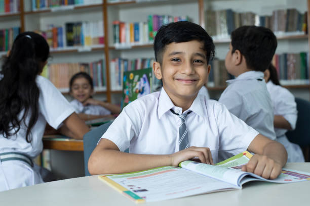 istock School children studying book at library 1351416428