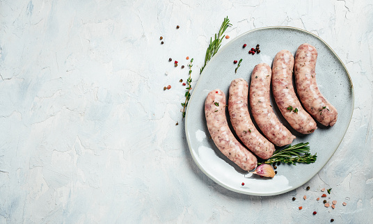 Traditional raw pork sausages on light background. Cooking ingredients. banner, menu, recipe place for text, top view.