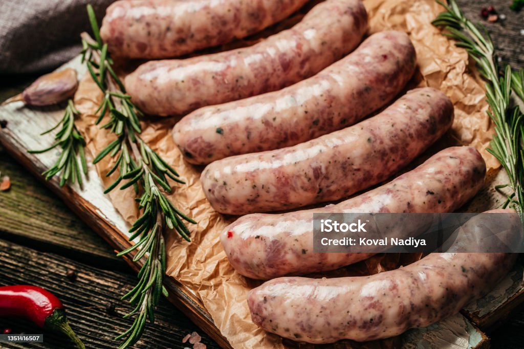 raw sausages with rosemary on a wooden background. Sausages for grilling. Food recipe background. Close up raw sausages with rosemary on a wooden background. Sausages for grilling. Food recipe background. Close up. Sausage Stock Photo