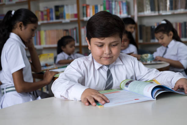 istock School children studying book at library 1351416535