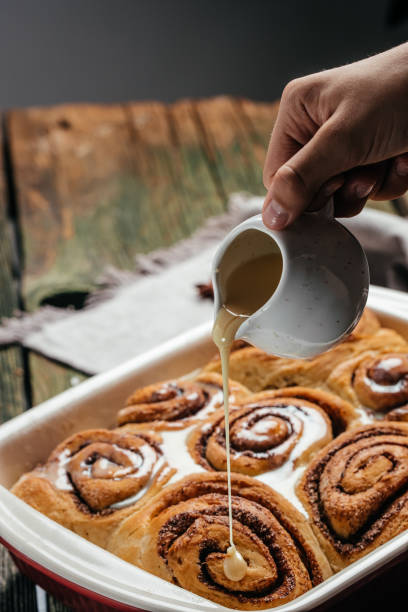 istock Sinnabon buns rolls. Woman's hand spreading vanilla cream 1351417242